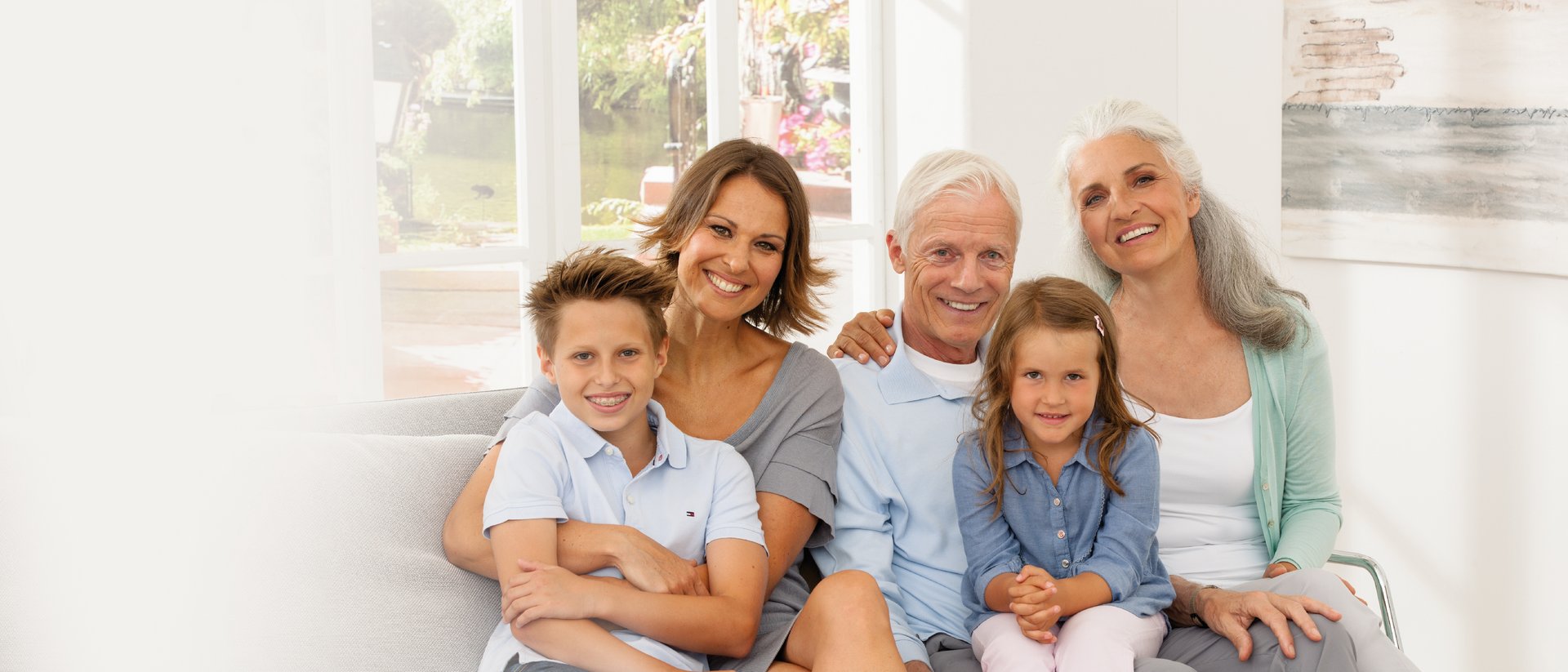 Das Bild zeigt eine lächelnde Familie auf dem Sofa 