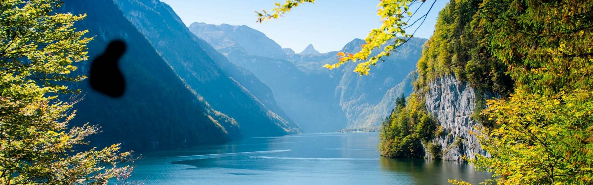 Blick auf eine Landschaft mit See, von dunklen Schatten am Bildrand eingeschränkt – typische Sicht bei Glaukom (Grüner Star)